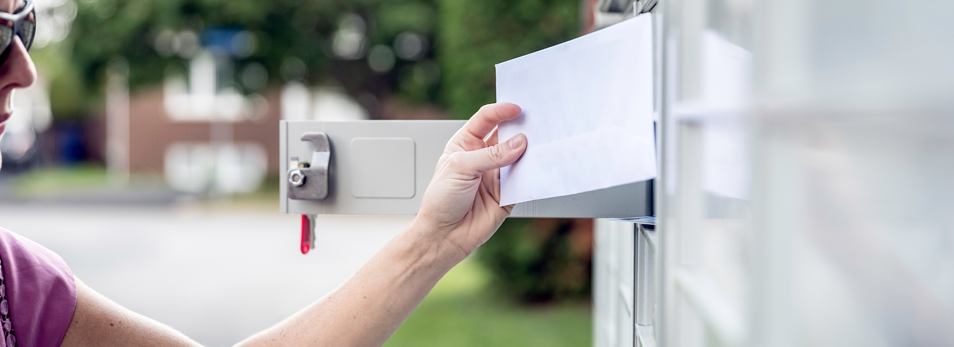 Consumer holding direct mail marketing envelope at mailbox