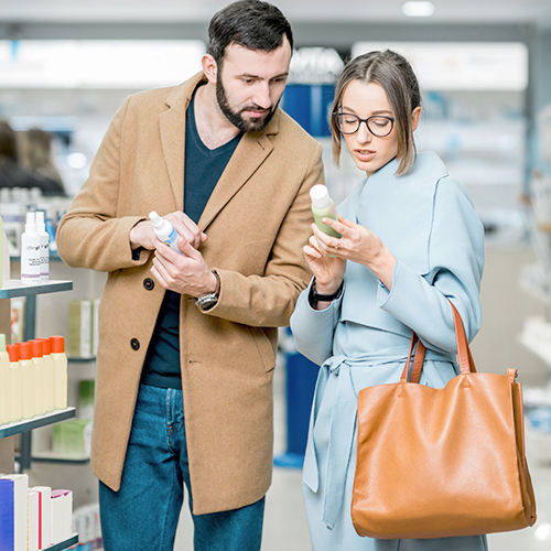 Consumers reading the label on a beauty and personal care product package in a retail setting