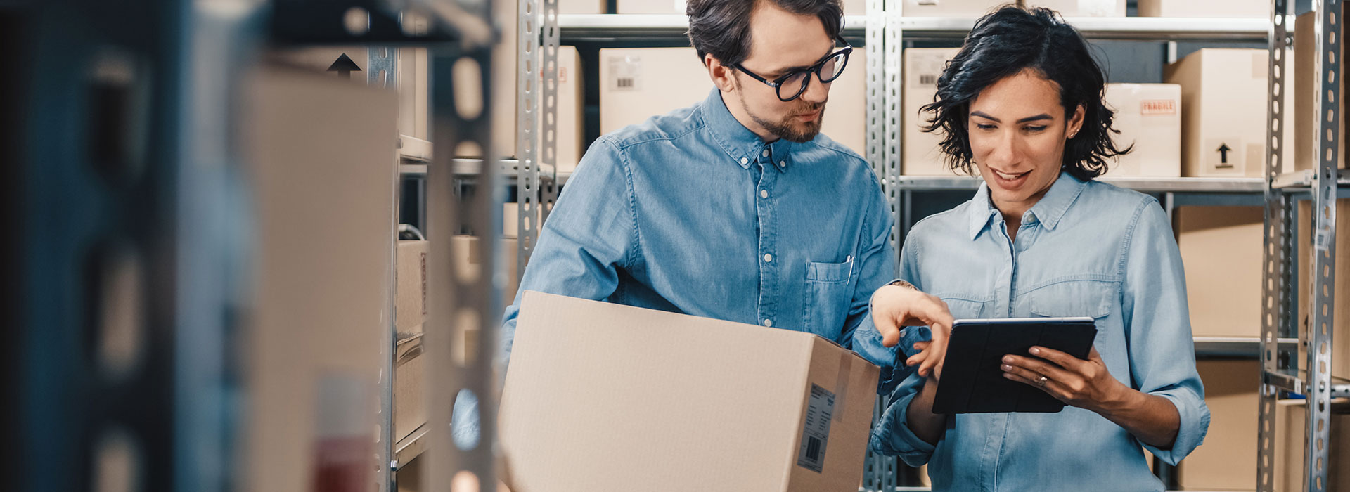 Warehousing and distribution employees in a warehouse setting check the status of a package delivery